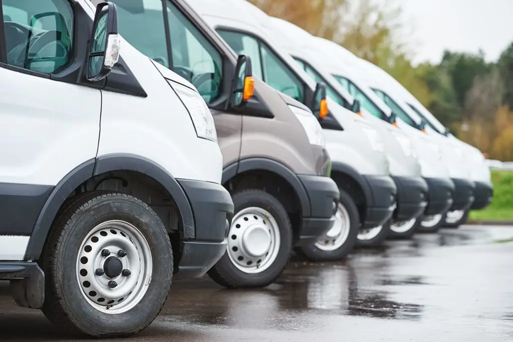 a line of white vans on wet tarmac